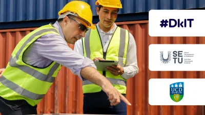 Two construction workers in yellow helmets and safety vests examining cargo containers.