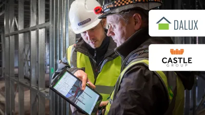 Construction worker in safety vest and hard hat reviewing information with supervisor at a construction site.