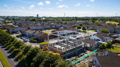 Aerial view of a housing development with construction site in center under blue sky.