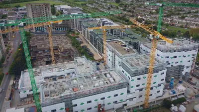 Aerial view of construction site with multiple cranes and partially built structures.
