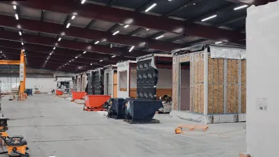 Large open warehouse or retail space under construction with wooden partitions, orange barriers, and industrial lights.