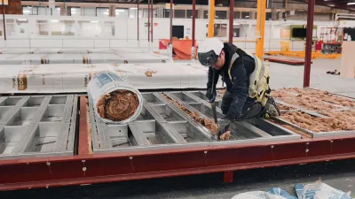 Person in safety gear operating heavy machinery on a large industrial flatbed.
