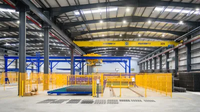 Interior of a large industrial warehouse with a yellow overhead crane and metal framework in a spacious facility.