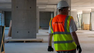 Construction worker in hard hat and high-visibility vest inspecting unfinished building interior.