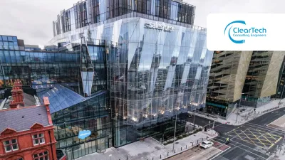 Modern glass office building beside a historic red brick structure on a city street.