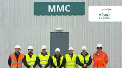 Six workers in hi-vis vests and hard hats stand in front of an MMC building with Mount Lucas logo.