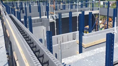 Construction site with concrete block walls and blue metal framework under a clear sky.