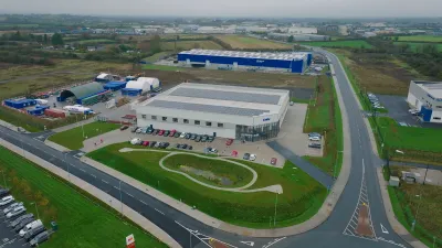 Aerial view of a modern industrial or logistics park with large blue warehouses and well-maintained roads.