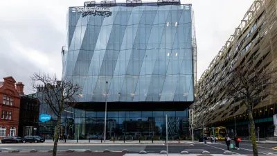 Modern glass office building on a city street corner on an overcast day.