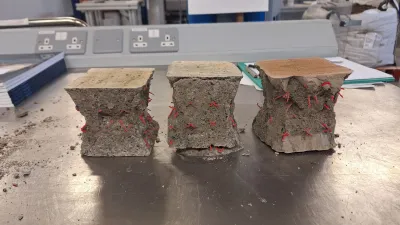 Three crushed concrete cube samples with red speckled pattern on a metal workshop surface.