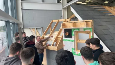 A group of students examining a wooden staircase frame model indoors.