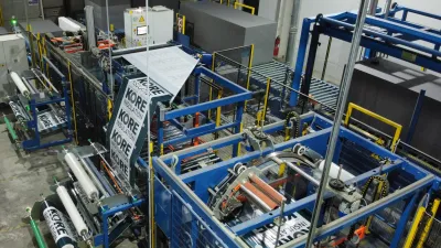 Overhead view of a large industrial manufacturing facility with blue metal framework and machinery.