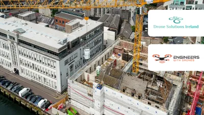 Aerial view of an active urban construction site with cranes, alongside a historic building.