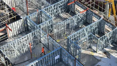 Aerial view of a construction site with steel formwork framework and workers in orange safety gear.