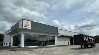 Modern commercial building with yellow triangle logo, large windows, and a truck parked outside.