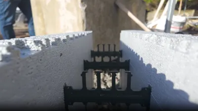Close-up of rebar and metal connector embedded in white foam insulation blocks at a construction site.