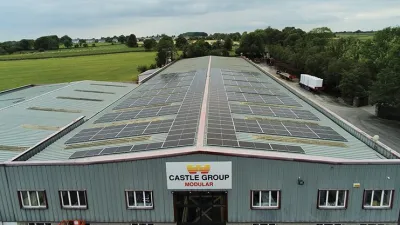Exterior of the Castle Group Modular manufacturing facility with solar panels covering the roof and a rural landscape in the background.