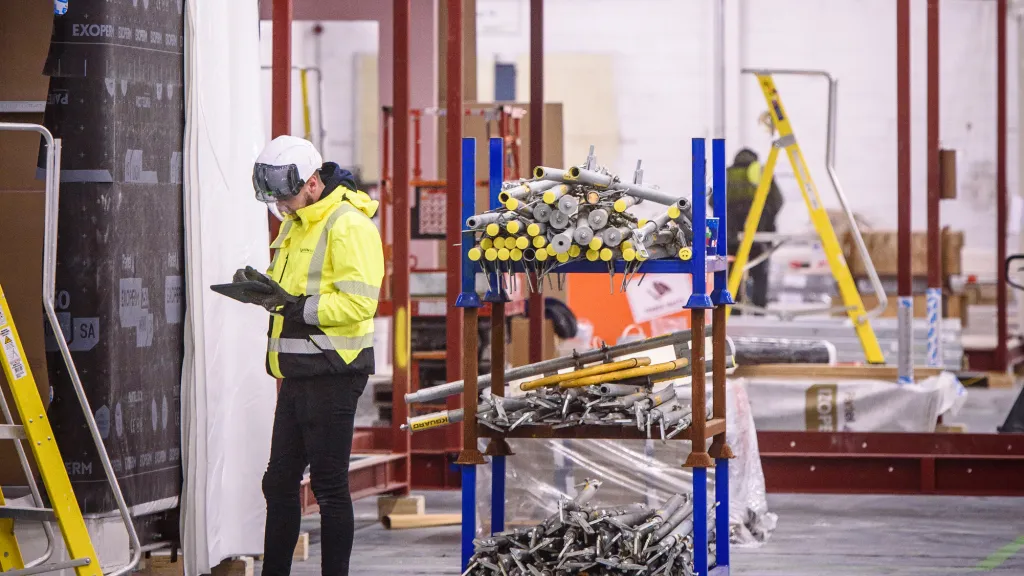 Workers in protective gear performing installation tasks inside an industrial facility