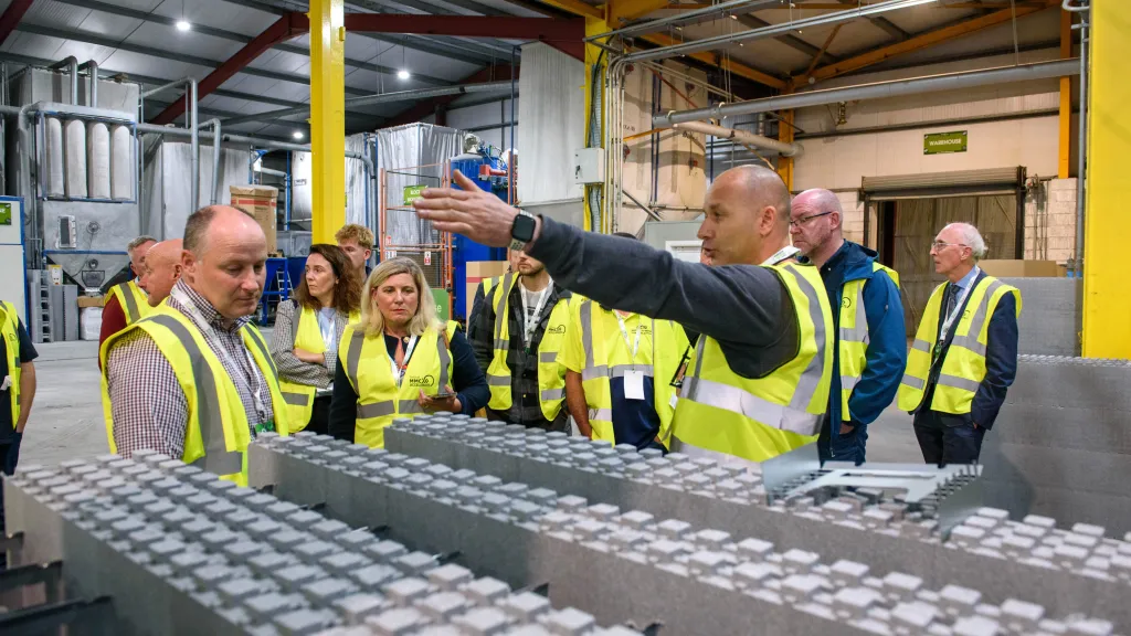 Group of workers in high-visibility vests inspecting an industrial assembly line.