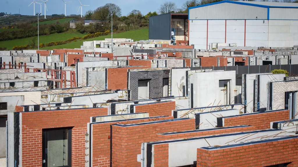 Rows of modern brick houses under construction in a dense residential development, overcast sky.