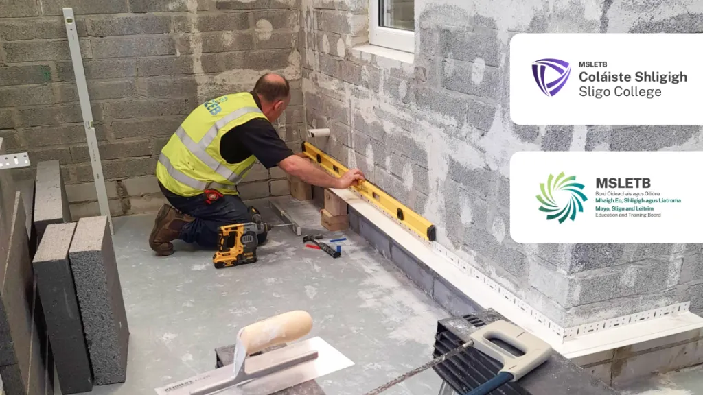 Worker in yellow vest using a level tool on a floor in a construction site, with two logos overlaid.