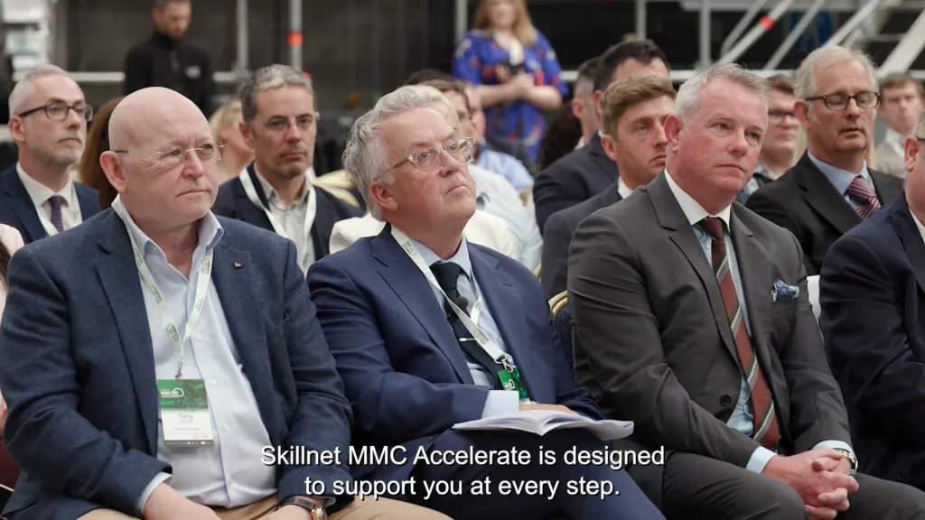 Audience of suited professionals attentively listening at a formal conference or business event.