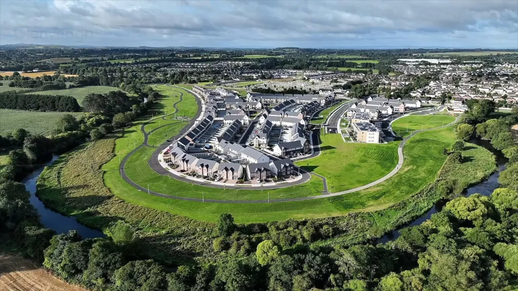 Aerial view of a horse racing track encircling a town, surrounded by green fields and a river.