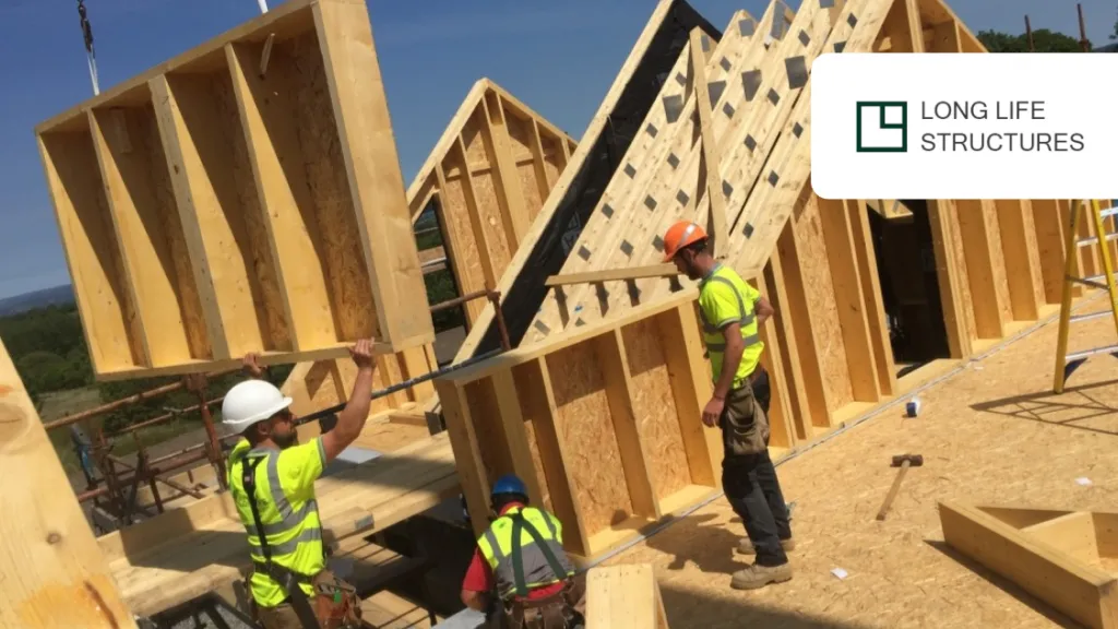 Construction workers in high-visibility vests assembling wooden wall frames for a new building.