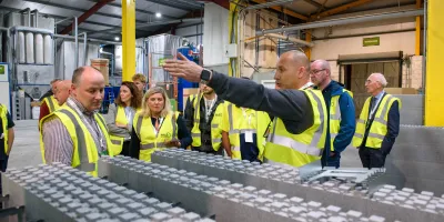 Group of workers in high-visibility vests inspecting an industrial assembly line.
