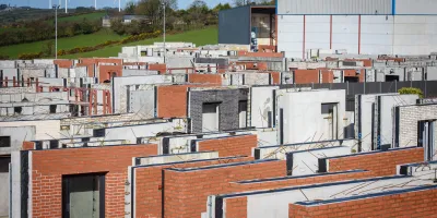 Rows of modern brick houses under construction in a dense residential development, overcast sky.
