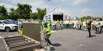 Workers in safety vests and hard hats gathered outdoors at an industrial facility during a demonstration.