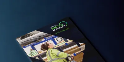Magazine cover featuring a worker in a yellow safety vest, displayed on a dark blue background.
