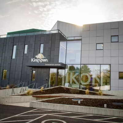 A modern grey building with large glasses windows and a sign for the company Kingspan above the entrance.