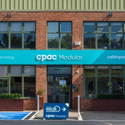 Exterior of brick building with light blue CPAC Modular above the entrance and Skillnner MMC Accelerate signboard outside the door.