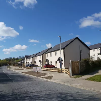 A row of modern white semi-detached houses beyond a wooden fence.