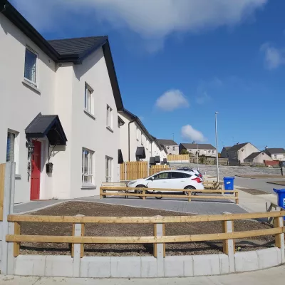 Two modern white semi-detached houses with a white car parked in the driveway.
