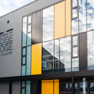 Modern grey school building with yellow and grey panels and glass windows.