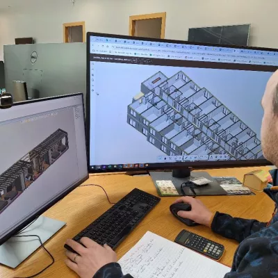 Man reviews digital building model on computer screen.