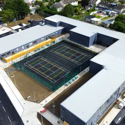 An overhead view of modern school U-shaped school buildings with two hockey courts in the centre.