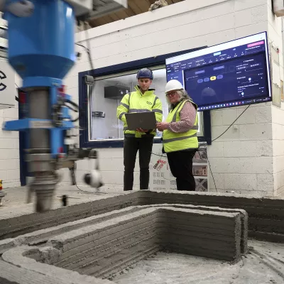 Two people operating a 3D concrete printing machine.