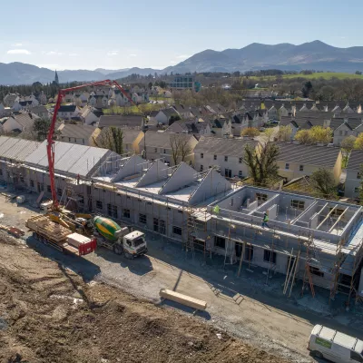 A large crane operating next to a number of houses under construction.
