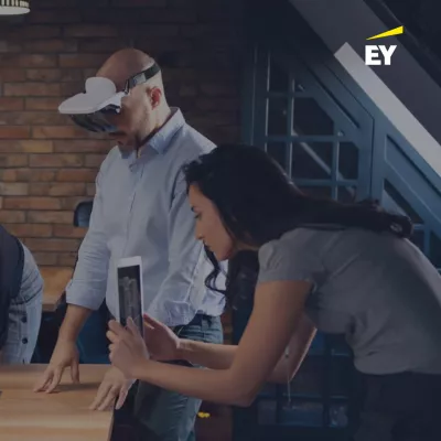 A female takes a photo of something with an tablet device while a male in a business shirt uses a VR headset.
