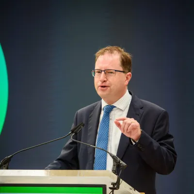 A man in a suit and tie speaking at a podium