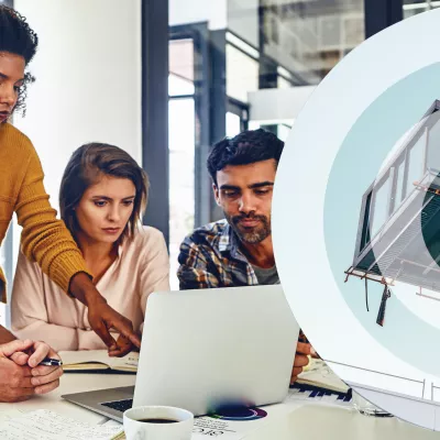 A group of office workers gather around a laptop. To the right, a modular building unit is hoisted by a crane.