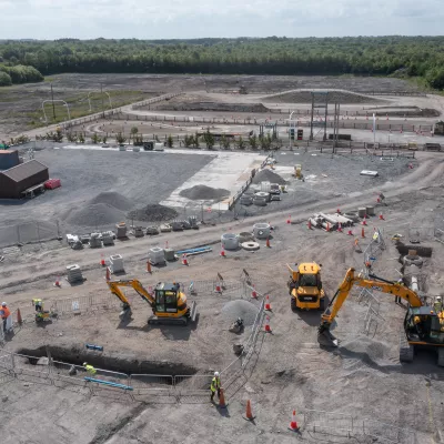 Diggers and construction workers on a dusty building site.