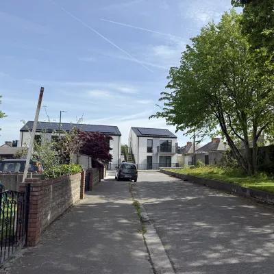 Two modern houses with black balconies at the end of a small suburban laneway.