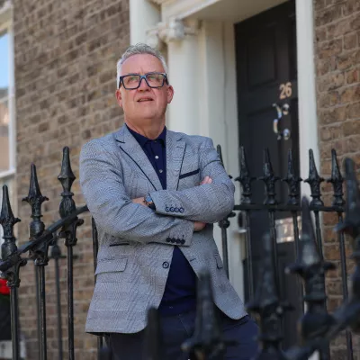 Person in a grey jacket standing outside a building.
