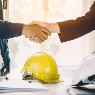 Two people wearing shirts shaking hands.