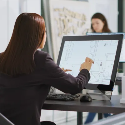 A person is seated in an office working on architectural design using a touchscreen device.