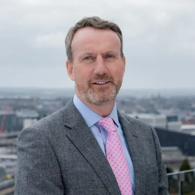 A man in a grey suit and pink tie